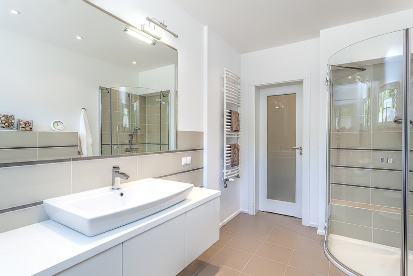 Salle de bains avec vasque, miroir et cabine de douche vitrée.