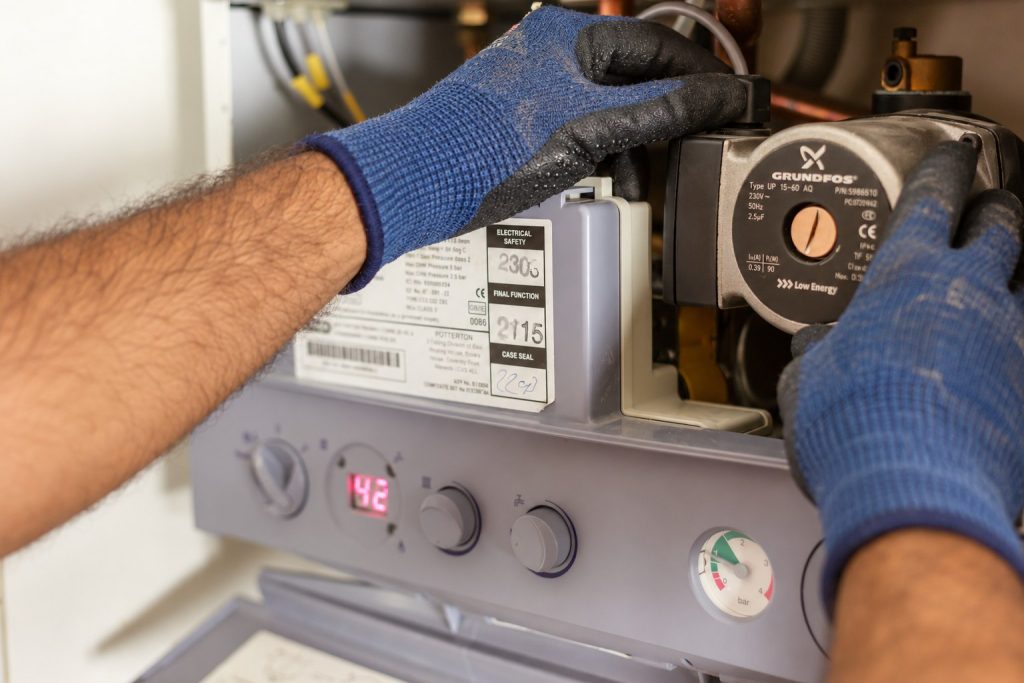 Mains gantées intervenant sur un circulateur dans un appareil de chauffage
