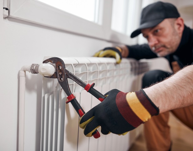 Technicien serrant un raccord de radiateur avec une clé